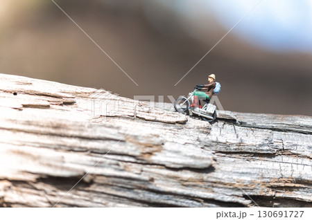 Miniature figurine of a man riding a motorcycle on a log Miniature figurine of a man riding a motorcycle on a log 130691727