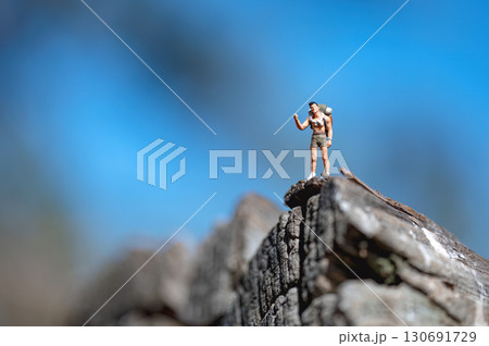 Miniature hiker celebrating reaching the top of a mountain 130691729