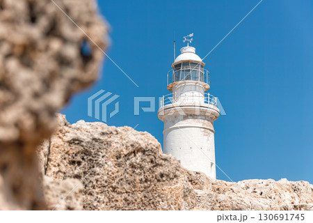 Paphos lighthouse rising high above the rocky coastline on a bright summer day with a clear blue sky. Cyprus 130691745
