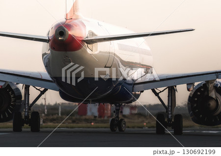 Modern passenger airplane taxiing on the runway during a beautiful sunset, preparing for takeoff or after landing Modern passenger airplane taxiing on the runway during a beautiful sunset, preparing for takeoff or after landing 130692199