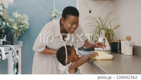 Cleaning, mom and child at kitchen counter, helping and learning chores, hygiene or home care. Housework, teaching and happy black woman with daughter, cloth and spray bottle for dust on furniture. 130692562