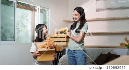 Family Bonding. Mother and daughter unpacking boxes in new home. 130692685