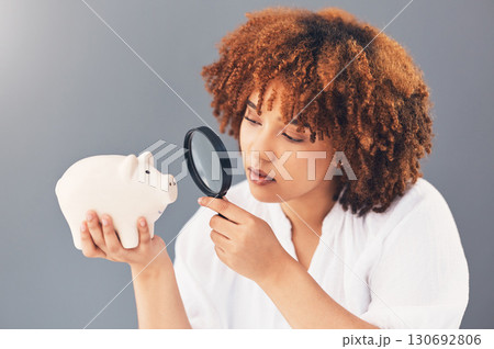 Magnifying glass, piggy bank or black woman with savings budget or financial profits growth on studio background. Curious, cash loan debt or broke girl searching for finances or money investment 130692806