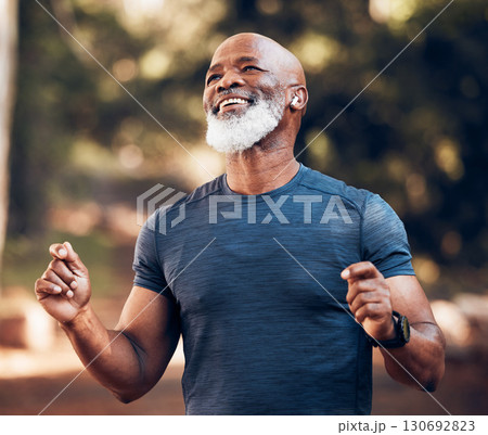 Park, success and running, winning black man excited and celebration at fitness run in nature with earphones. Music, workout and mature runner with smile and happy to celebrate exercise achievement. 130692823
