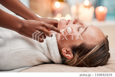 Face massage, roller and woman at spa with therapist, treatment and skincare, self care and rose quartz. Holistic therapy at luxury resort, healthy skin and wellness, hands and massaging with beauty 130692829