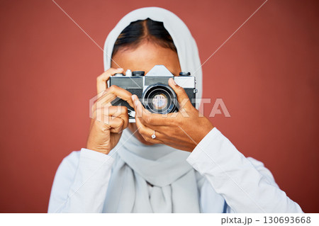 Photography, muslim woman taking picture with camera and mockup with smile isolated on red background. Creative professional lifestyle photographer in hijab, hobby or career taking photo in studio. 130693668