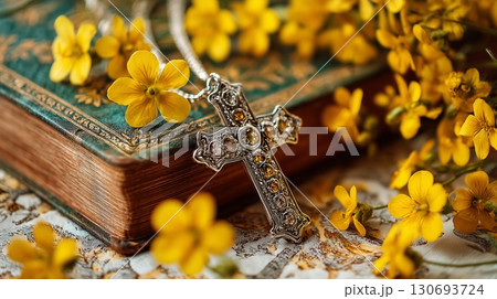 Inspiring cross of Jesus Christ resting on a holy bible surrounded by beautiful yellow flowers in a prayerful worship atmosphere 130693724