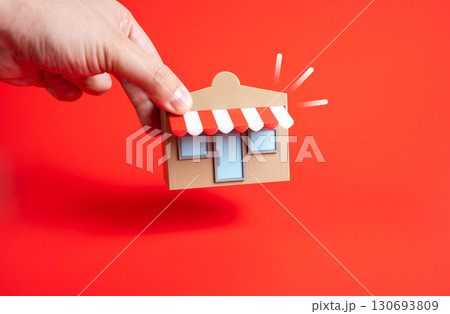 Hand places store on ground. Concept of entrepreneurship, retail opening, and small business development. Suitable for startups, local economy, and commerce growth. 130693809