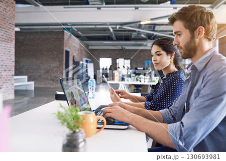 Teamwork, office and laptop, man and woman at desk with laptop at creative agency, working on project together. Leadership, partnership and happy employees or business partner at design startup. 130693981