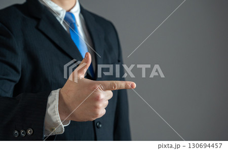Businessman points his finger. To attract attention. To confidently show what to pay attention to. Space for text, copy space, leadership concept, business direction, decision making. Businessman points his finger. To attract attention. To confidently show what to pay attention to. Space for text, copy space, leadership concept, business direction, decision making. 130694457