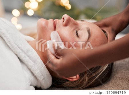 Beauty, gua sha and woman getting a facial massage for wellness, health and self care at a spa. Skincare, cosmetic and calm young female doing a luxury face treatment with rose quartz at a zen salon. Beauty, gua sha and woman getting a facial massage for wellness, health and self care at a spa. Skincare, cosmetic and calm young female doing a luxury face treatment with rose quartz at a zen salon. 130694719