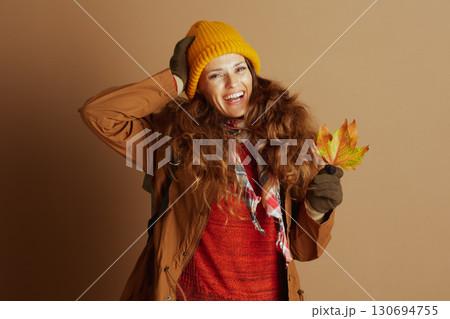 Cheerful Woman Posing with Autumn Leaf 130694755