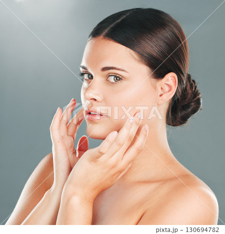 Woman, portrait and face in beauty for skincare, makeup or cosmetics isolated against a gray studio background. Beautiful female touching smooth, soft or perfect skin in satisfaction for treatment 130694782
