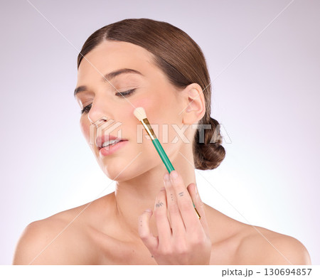 Face, beauty and brush with cosmetics and woman with makeup tools on studio background. Facial, cosmetology and healthy skin glow with color, skincare and hand with foundation shine and elegant 130694857