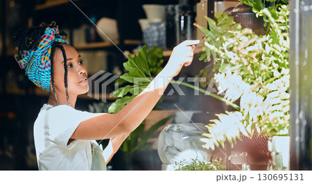 Small business, black woman and entrepreneur as a florist at a plant shop in the gardening in a nursery. Sustainability, growth and store owner working with green plants in a greenhouse startup Small business, black woman and entrepreneur as a florist at a plant shop in the gardening in a nursery. Sustainability, growth and store owner working with green plants in a greenhouse startup 130695131