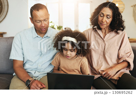 Child streaming a movie on laptop with her grandparents while relaxing on sofa in the living room. Technology, rest and girl watching video or film with grandfather and grandmother for entertainment. Child streaming a movie on laptop with her grandparents while relaxing on sofa in the living room. Technology, rest and girl watching video or film with grandfather and grandmother for entertainment. 130695262