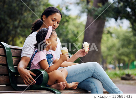 Summer, garden and ice cream with a mother and daughter bonding together while sitting on a bench outdoor in nature. Black family, children and park with a woman and girl enjoying a sweet snack 130695435