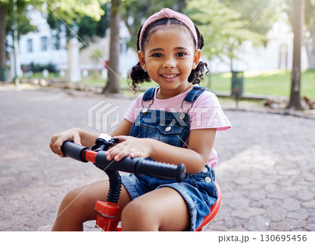 Portrait, young girl on bike in park and happy child outdoor with nature and freedom, smile while riding. Travel, happiness and adventure, growth and childhood with family day out and cycling mockup 130695456