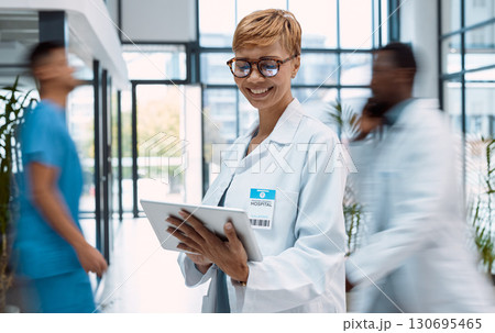 Tablet, doctor and black woman in busy hospital or clinic for research, telehealth or online consultation. Healthcare app, technology and smile of happy senior medical professional with touchscreen. Tablet, doctor and black woman in busy hospital or clinic for research, telehealth or online consultation. Healthcare app, technology and smile of happy senior medical professional with touchscreen. 130695465