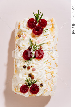 Elegant raspberry meringue roll cake on pink background with festive decoration Elegant raspberry meringue roll cake on pink background with festive decoration 130695552