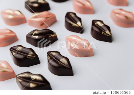 Luxury lip shaped chocolate candies with gold decor on pastel background 130695569