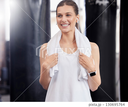 Woman, fitness and smile with towel in gym after workout, sweating and training. Happy sports female thinking of wellness in exercise club for health, performance and happiness with music earphones 130695764