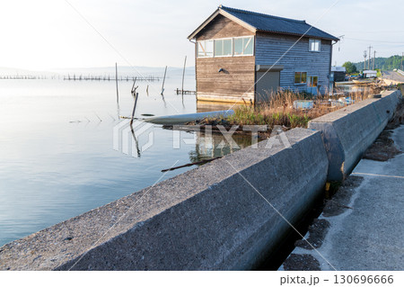 堤防と陸地の隙間が空いたままの海岸線と浸水したままの倉庫 130696666