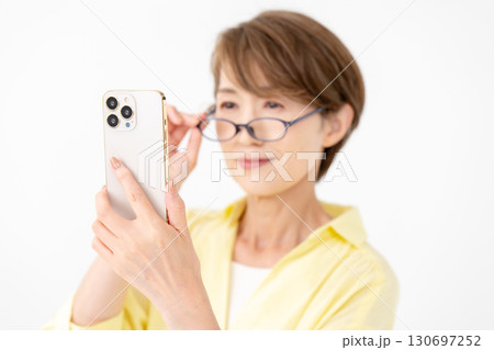 老眼鏡でスマホを見る女性 老眼鏡でスマホを見る女性 130697252
