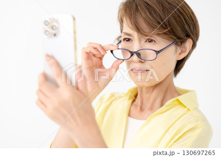 老眼鏡でスマホを見る女性 130697265