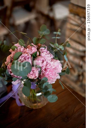 Beautiful pink peonies in a round glass vase with transparent walls. Bridal bouquet or home decoration. Beautiful pink peonies in a round glass vase with transparent walls. Bridal bouquet or home decoration. 130697339
