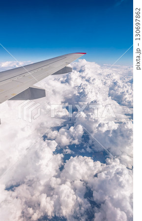 View from the airplane window at a beautiful cloudy sky and the airplane wing View from the airplane window at a beautiful cloudy sky and the airplane wing 130697862