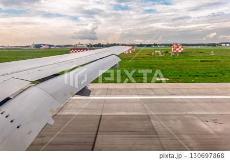 View of airplane wing, blue skies and green land during landing. Airplane window view. 130697868