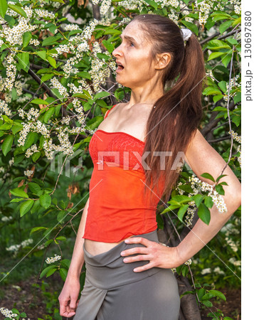 Young woman sneezes in the park against the background of a flowering tree. Allergy to pollen concept. Young woman sneezes in the park against the background of a flowering tree. Allergy to pollen concept. 130697880