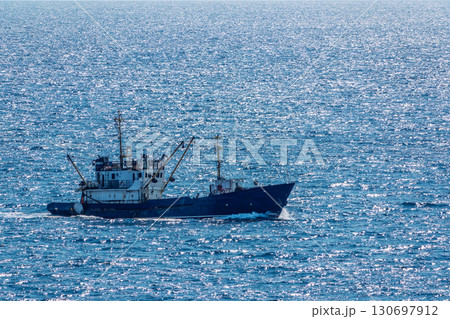 Fishing boat in blue sea and clear sky with birds flying overhead. Fishing boat in blue sea and clear sky with birds flying overhead. 130697912