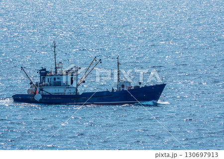 Fishing boat in blue sea and clear sky with birds flying overhead. 130697913