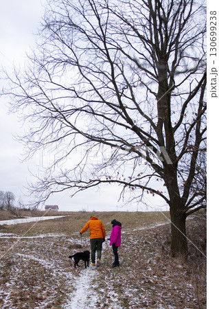 Walking through a winter landscape with a playful dog, enjoying the serene beauty of nature on a chilly day in an open field Walking through a winter landscape with a playful dog, enjoying the serene beauty of nature on a chilly day in an open field 130699238