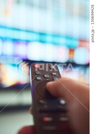 Watching television with remote control Watching television with remote control 130699426