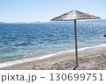 An umbrella on the empty beach. A seashore background with an umbrella. A seascape frame with copy space. Travelling and tourism background. 130699751