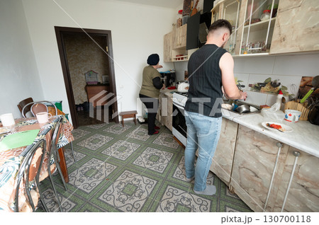 Two individuals engaged in cooking and cleaning in a cozy kitchen setting, creating a warm atmosphere filled with daily life activities, showcasing the harmony of shared moments 130700118