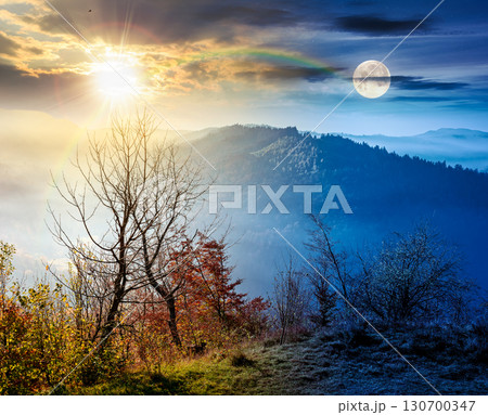 view from a mountain in to the foggy valley. day and night time change concept. beautiful autumn equinox. forested hills with sun and moon at twilight. picturesque alpine countryside scenery view from a mountain in to the foggy valley. day and night time change concept. beautiful autumn equinox. forested hills with sun and moon at twilight. picturesque alpine countryside scenery 130700347