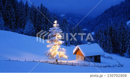 Cozy Winter Night with Illuminated Christmas Tree and Snow Covered Cabin in Forest 130702808