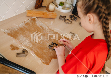 Girl in festive New Year pajamas baking cookies in the kitchen, holiday family tradition 130703186