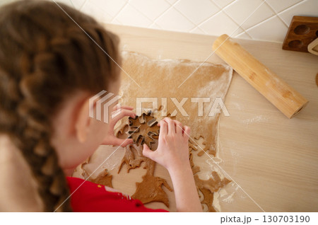 A girl in pajamas is preparing New Year cookies in the kitchen. 130703190