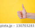 A hand giving a thumbs-up gesture against a yellow background. 130703283