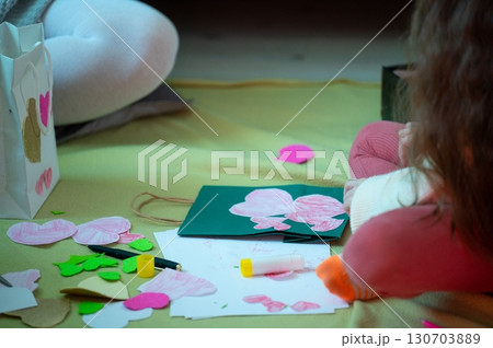 A child crafts heart-shaped decorations, showcasing creativity and festive preparation. 130703889