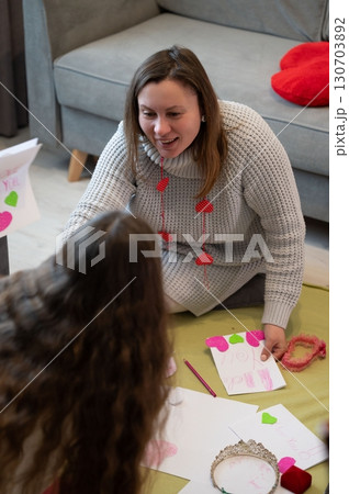 A woman and child create Valentine's Day cards together, sharing a heartwarming moment of crafting and love. A woman and child create Valentine's Day cards together, sharing a heartwarming moment of crafting and love. 130703892