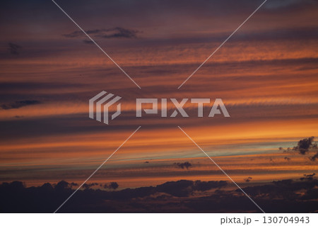 Sky transforms with vibrant hues during a stunning sunrise over the horizon, illuminating the clouds 130704943