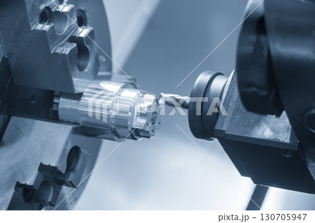 The CNC lathe machine drilling process on metal shaft parts by center drill tool in the blue tone. The CNC lathe machine drilling process on metal shaft parts by center drill tool in the blue tone. 130705947