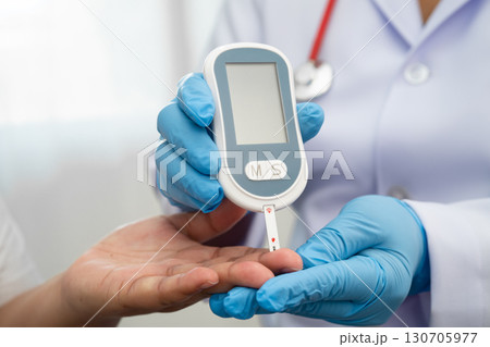 Doctor check diabetes from finger blood sugar level with digital glucose monitor measure and test stripe. 130705977