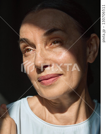Mature woman with soft smile in sunlight highlighting natural skin texture Mature woman with soft smile in sunlight highlighting natural skin texture 130706511